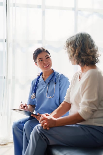 Female nurse asking woman patient questions and writing them down