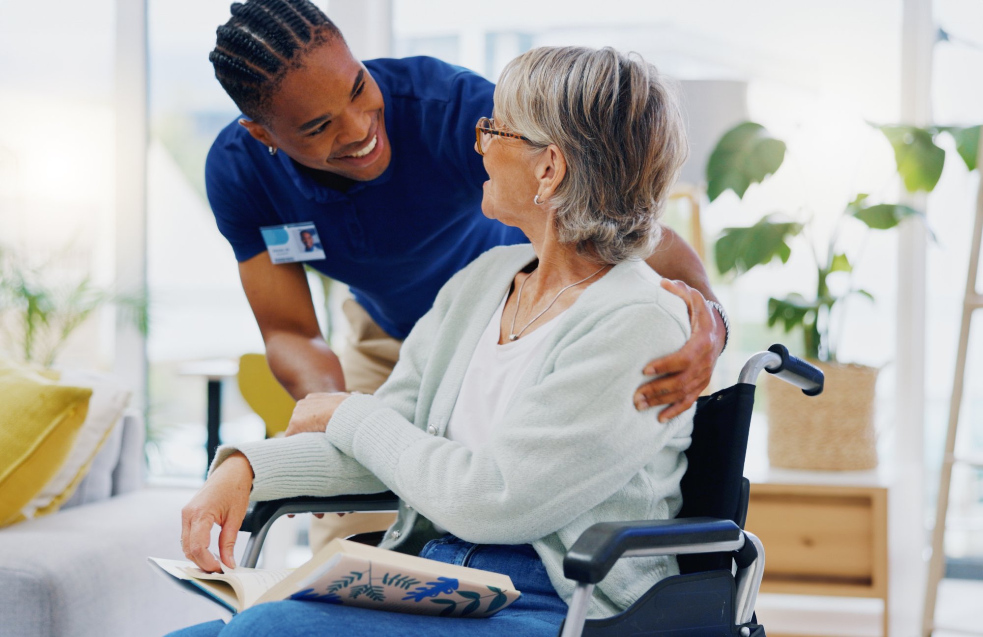 Male nurse welcoming an older woman patient sitting in a wheelchair